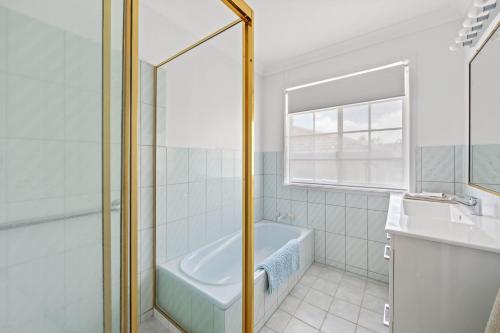 a white bathroom with a tub and a window at Waterfront Paradise in Tweed Heads