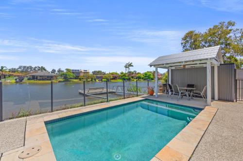 a swimming pool with a gazebo next to a lake at Waterfront Paradise in Tweed Heads