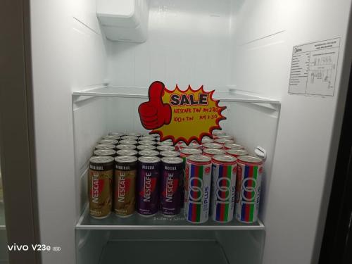 a refrigerator with a sale sign and cans of soda at HANS HOMESTAY in Lumut