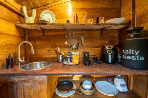 a kitchen counter with a sink in a wooden cabin at Salty Siesta Stays in Selong Belanak