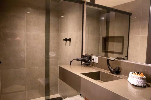 a bathroom with a sink and a shower with a mirror at Motel Caricia (Adult Only) in Rio de Janeiro