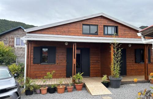 a wooden house with potted plants in front of it at Les Cattleyas in Saint-Joseph
