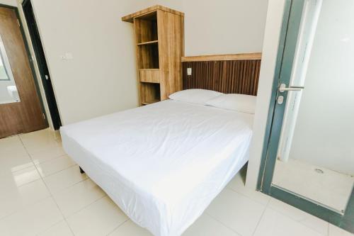 a bedroom with a white bed and a wooden cabinet at Aurora Rooms Riverdale in Rawasuren