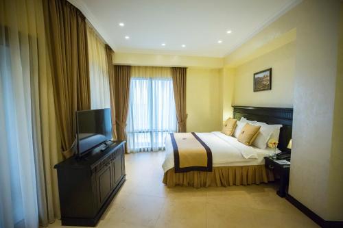 a hotel room with a bed and a television at Colosseum Marina Hotel in Batumi