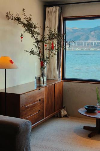 a living room with a dresser with a large window at Dali Shuanglang Anqi'erhai Resort Hotel in Dali Shuanglang