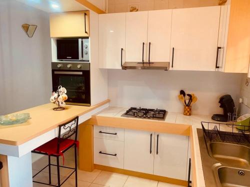a kitchen with white cabinets and a stove top oven at Résidence du Récif - L'Hirondelle in Bain Boeuf