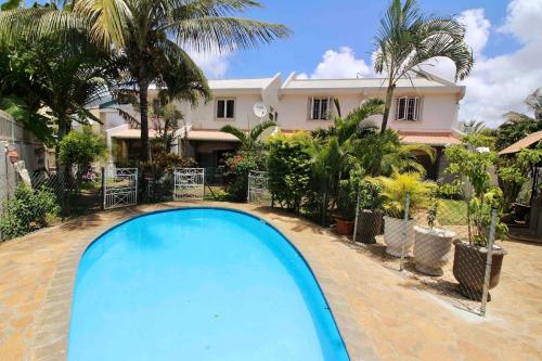a swimming pool in front of a house at Résidence du Récif - Le Perroquet in Bain Boeuf