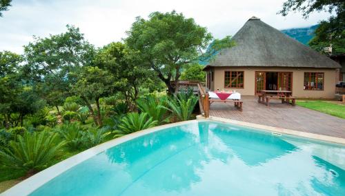 a villa with a swimming pool in front of a house at Amafu Forest Lodge in Hoedspruit