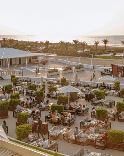 a group of people sitting at tables at a beach restaurant at Sea Breeze Resort, Beachfront apartment with a balcony and sea view in Nardaran