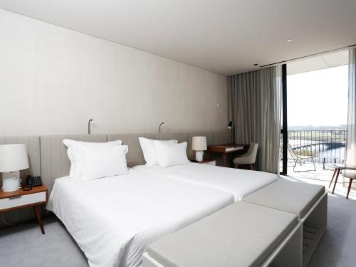 a bedroom with a large white bed and a balcony at Montebelo Vista Alegre Ílhavo Hotel in Ílhavo