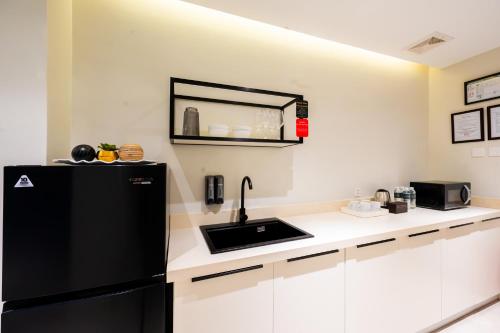 a kitchen with a black refrigerator and a sink at SixtyFifth Destination Resort Hotel in Bacolod