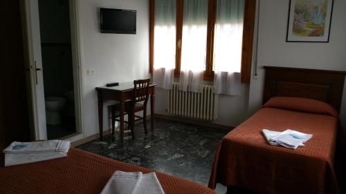 a room with two beds and a table and a window at Albergo Sonia in Florence