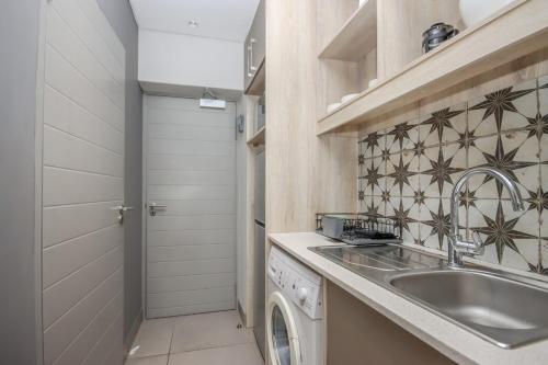 a kitchen with a sink and a washing machine at 18 on The Den Studio Apartment in Stellenbosch