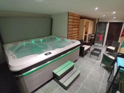 - une grande baignoire dans une chambre avec une table et des chaises dans l'établissement Perce neige, à Morillon