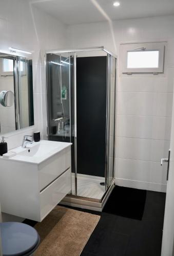 une salle de bain blanche avec une douche et un lavabo dans l'établissement Les Pierres Marines, au Conquet