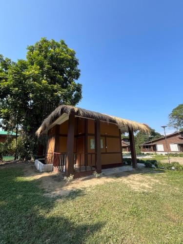 a small hut with a grass roof on a field at Jironi Resort in Tezpur