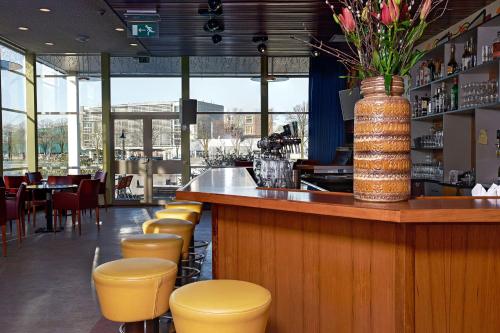 a bar with yellow stools and a vase of flowers at Pension Homeland in Amsterdam