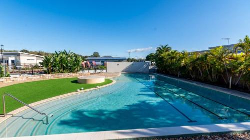 a swimming pool with a green lawn and trees at 'serenity On Spinnaker' in Sandstone Point