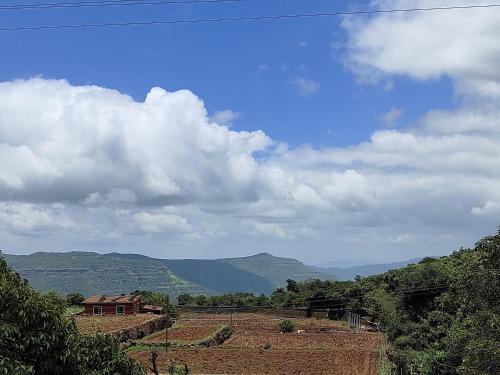 a view of a field with mountains in the background at Woodland farm vila in Mahabaleshwar
