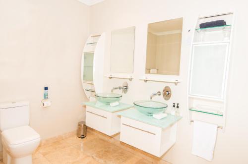 a bathroom with two sinks and a toilet at 61 on Camps Bay in Cape Town