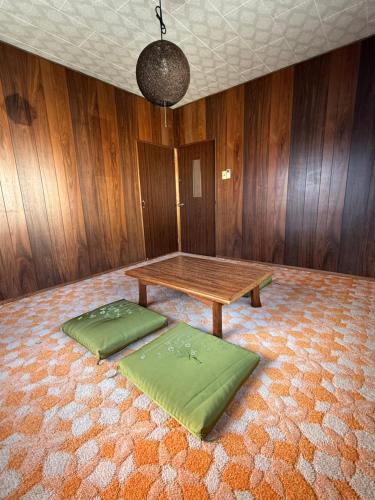 a room with a wooden table and two green mats at ゲストハウス 庵 Ann in Nachikatsuura