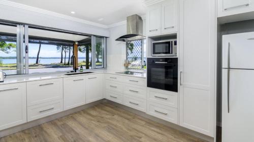 Una cocina con gabinetes blancos y una ventana grande. en 'bribie Beach Apartment', en Bellara