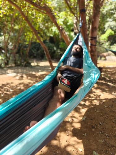 a man sitting in a hammock in a park at Gaia Ekole in Āmbavna