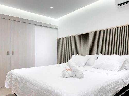 a bedroom with a large white bed with white pillows at Airbnb Guayaquil, Mall del Sol, Piso alto in Guayaquil