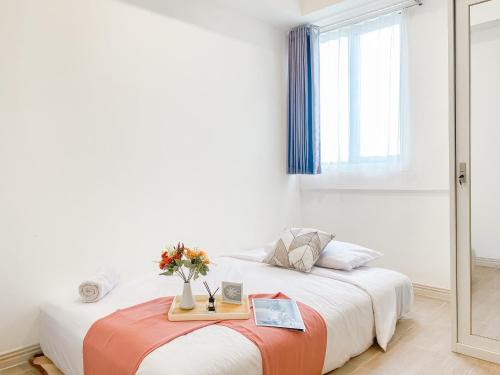 芝卡朗Good Place and Elegant 3BR Meikarta Apartment By Travelio的一间卧室，有两张床和一张摆满鲜花的桌子