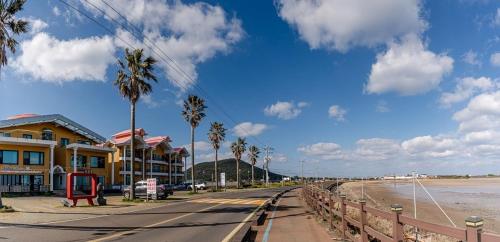 a street with a house and palm trees on the beach at Jeju Sol Pension Jeju Sunrise from the Room in Chung-dong