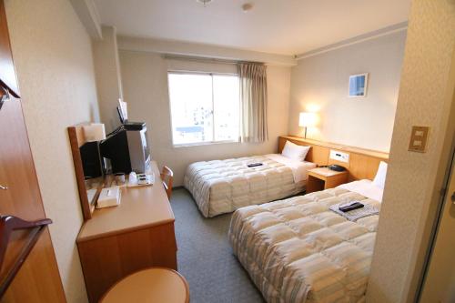 a hotel room with two beds and a television at South Breeze Hotel Kochi Kaigetsu in Kochi