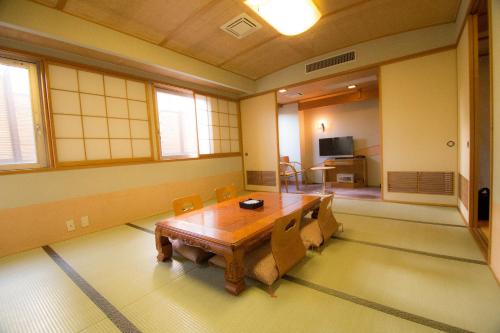 a dining room with a wooden table and chairs at South Breeze Hotel Kochi Kaigetsu in Kochi
