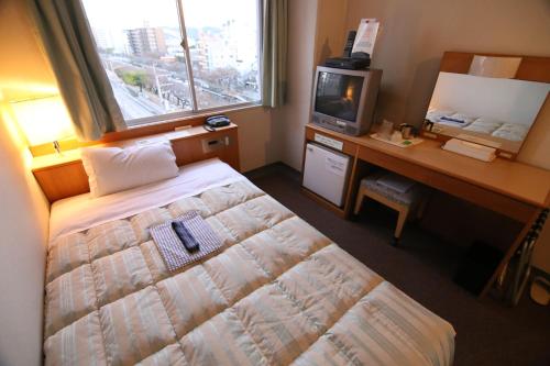 a bedroom with a bed and a desk and a television at South Breeze Hotel Kochi Kaigetsu in Kochi