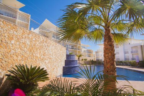 eine Palme vor einem Gebäude mit Pool in der Unterkunft Luxury Apartment Ocean View by Be Cherish in Albufeira