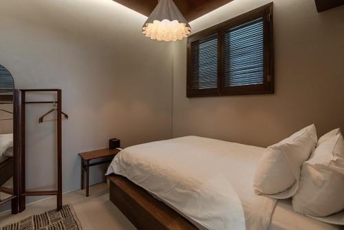 a bedroom with a white bed and a chandelier at Jeju Rapauza Stay in Yusuam