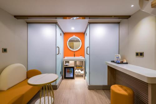 a bathroom with an orange wall and a table at Dequan Luxury HotelGuomao BranchThe subway is right outside the door Coffee, fruits, snacks, a gym and a laundry room are provided for free in the lobby in Beijing