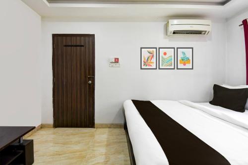 a bedroom with a bed and a brown door at Super Hotel O New Alipore in Kolkata
