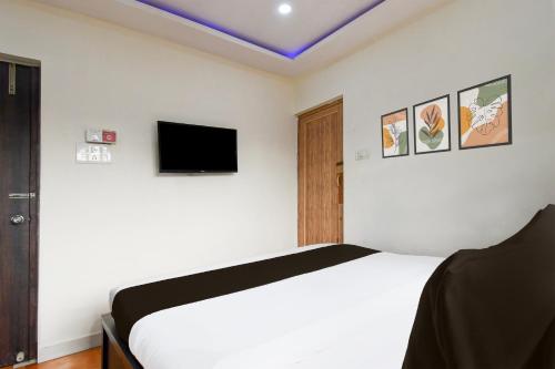 a bedroom with a white bed and a tv at Super Hotel O New Alipore in Kolkata