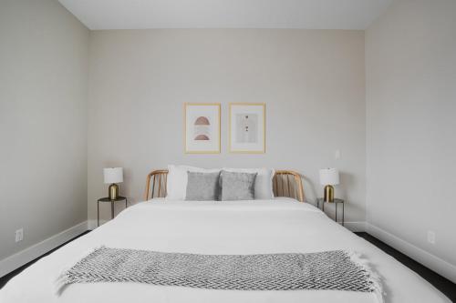 a white bedroom with a large white bed with two lamps at Blueground Burlingame ac wd nr park SFO-1791 in San Francisco