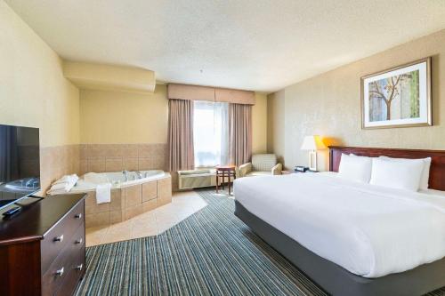a hotel room with a large bed and a tub at Quality Inn & Suites Yorkton in Yorkton