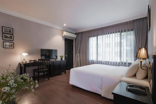 a hotel room with a white bed and a desk at La Passion Classic Hotel in Hanoi
