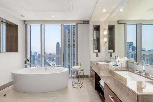 a bathroom with a large tub and large windows at Hilton Dubai Al Habtoor City in Dubai