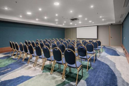 a conference room with a row of chairs and a screen at Hilton Porto Alegre, Brazil in Porto Alegre
