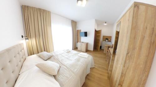 a white bedroom with a bed and a table at Przystań Admiralska 11 in Jarosławiec