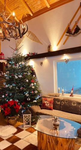 a christmas tree in a living room with a couch at Planinska kuća Ema in Kupres