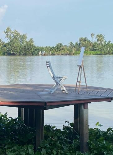 a wooden dock with a chair and a painting on it at บ้านพระจันทร์เวียน - House of moon phase in Chachoengsao