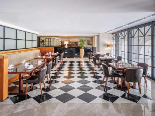 a restaurant with tables and chairs on a checkered floor at The Hotel Galleria Jeddah, Curio Collection by Hilton in Jeddah