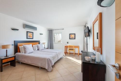 a bedroom with a bed and a television in it at Comfortable Duplex Apartment with 2 bedrooms & 2 terraces 200 m away from the Ocean in Porches