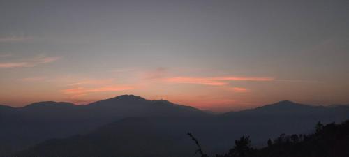 a sunset over a mountain range with mountains in the background at Into the mountain in Pokhara