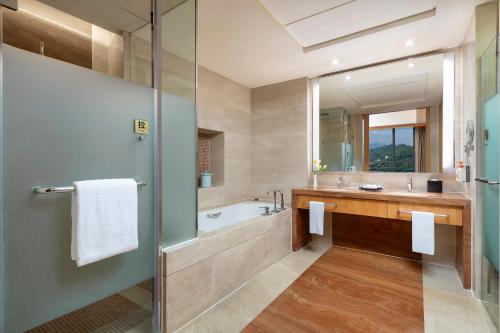 a bathroom with a tub and a sink and a mirror at Crowne Plaza Yichang by IHG in Yichang